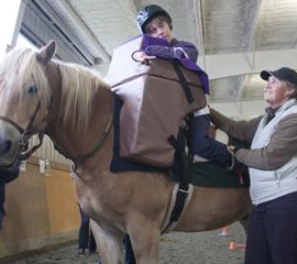On delivery day, Whitney is excited to finally be able to sit upright and see where she's going while riding Danny. Whitney's instructor, Stella (shown right), stands nearby at all times.