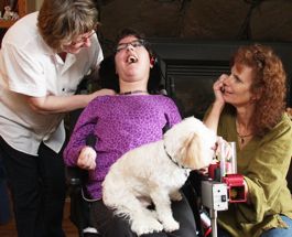 Bear, comfortably seated on Shayla's lap, checks out the ball launcher. Sandra is shown on the left.