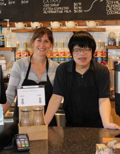 A youth and employer pose for a photo in a cafe.